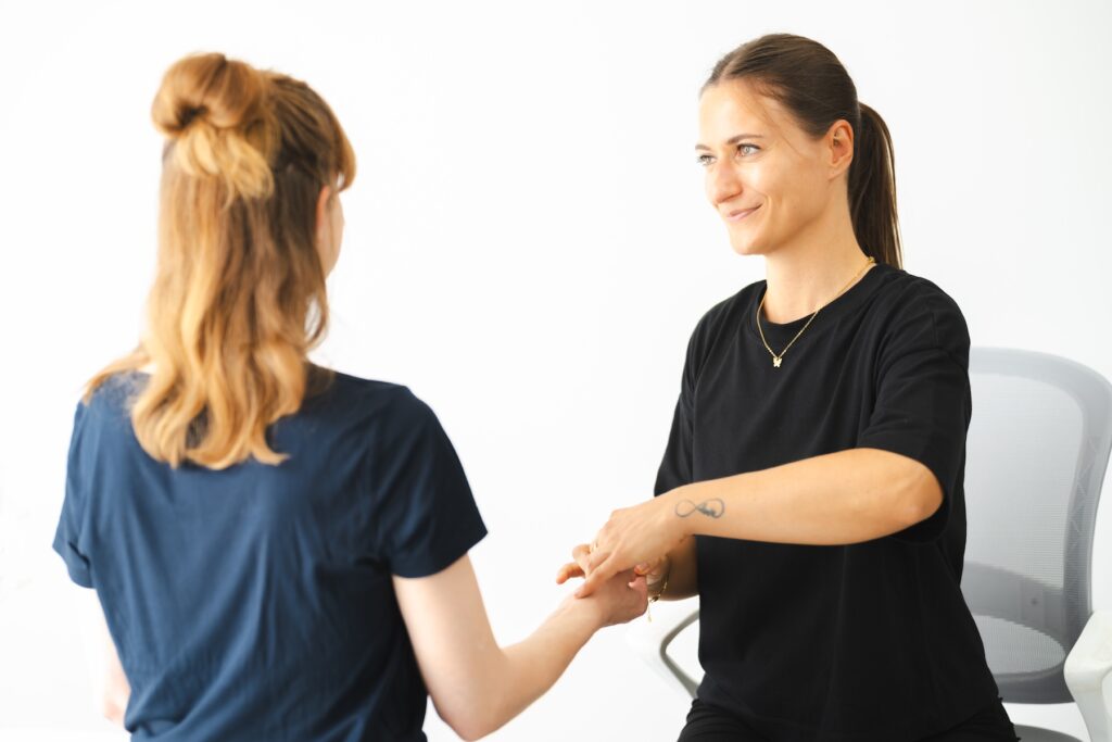 wingwave Coach Giulia Barile, gekleidet in schwarzer Hose und Shirt, führt den Myostatiktest bei ihrer Klientin durch