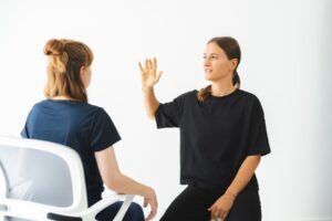 wingwave Coach Giulia Barile, gekleidet in schwarzer Hose und Shirt, erzeugt schnelle rechts-links Augenbewegungen bei ihrer Klientin, indem sie ihre Hand vor den Augen ihrer Klientin schnell hin und her bewegt